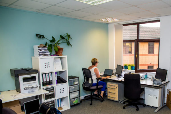 A Welsh ICE office space with a desks, storage shelves and monitors.